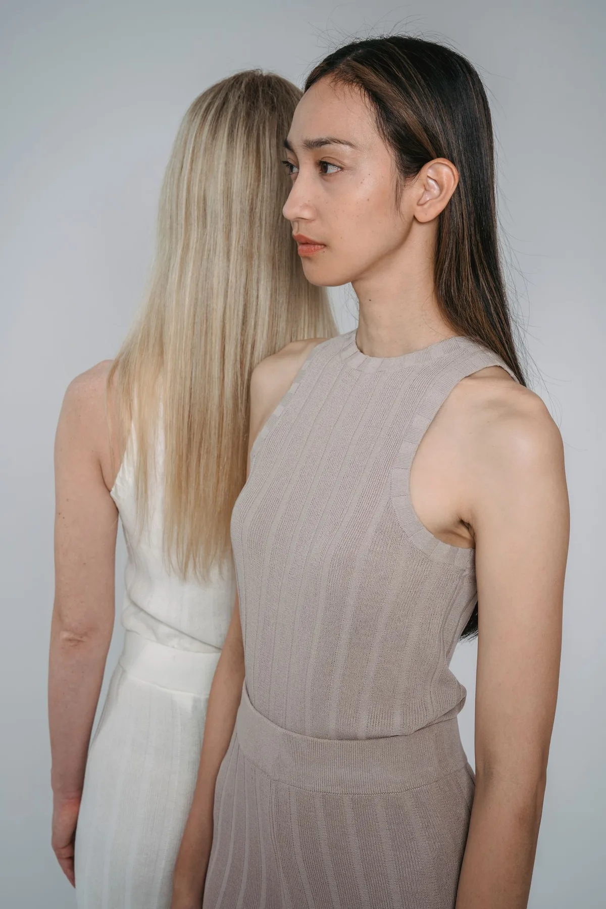 Two fashion models wearing elegant beige and ivory dresses